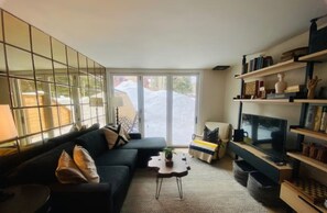 A modern living room with a black sofa, a coffee table, a TV, and a bookshelf.