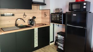 Une cuisine compacte équipée d’un four à micro-ondes, d’un grille-pain et d’un réfrigérateur, ainsi que d’un petit évier et d’un plan de travail en bois.