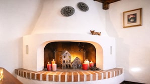 Une cheminée au design rustique, agrémentée d’une petite maquette de maison et de bougies.