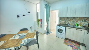 A modern kitchen with a washing machine, a dining area with a glass table, and a living space with a sofa. - Seafront Sea View Maisonette with Yards (St. Paul's Bay)