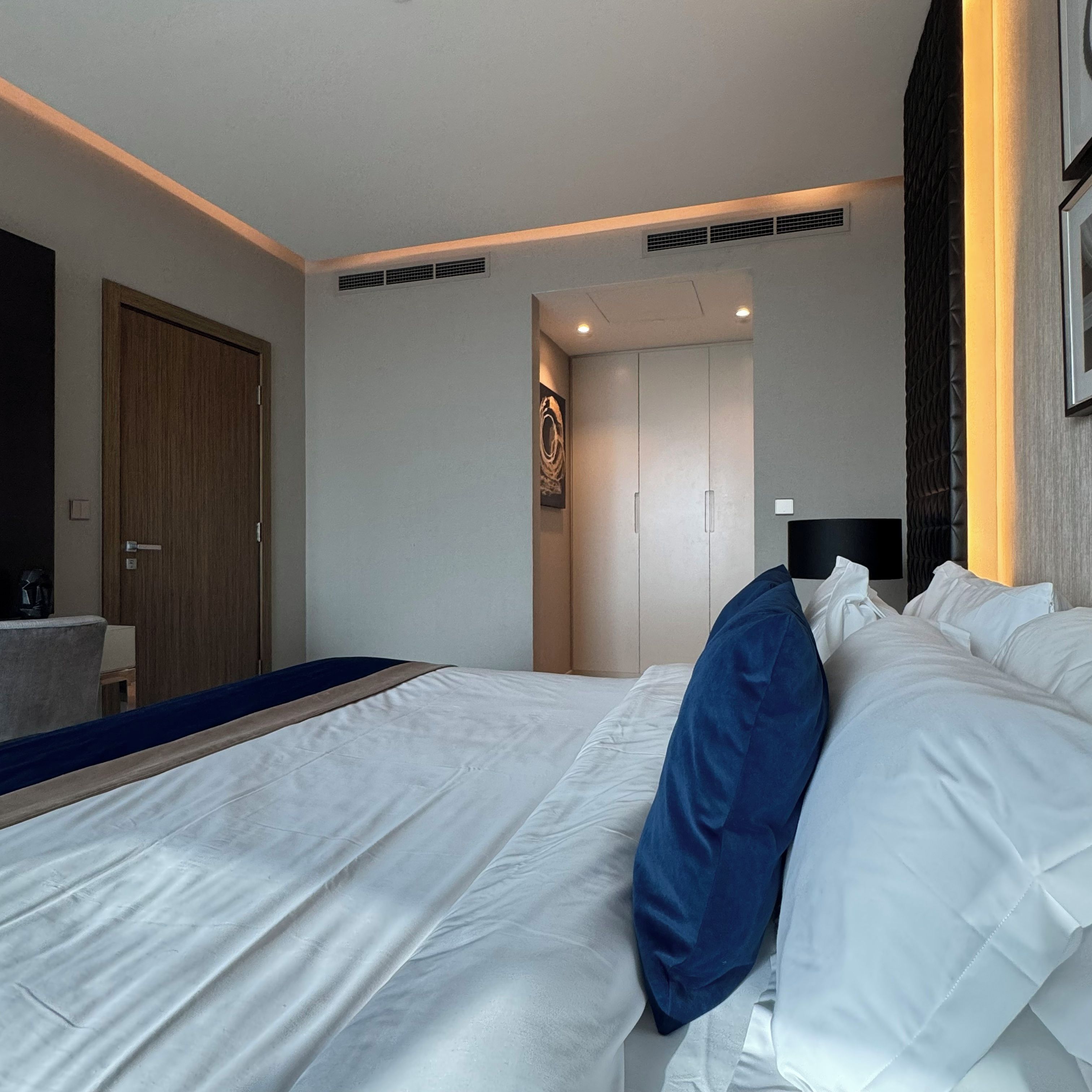 Une chambre d’hôtel avec un grand lit, une porte en bois et une petite table sur laquelle se trouve une machine à café.