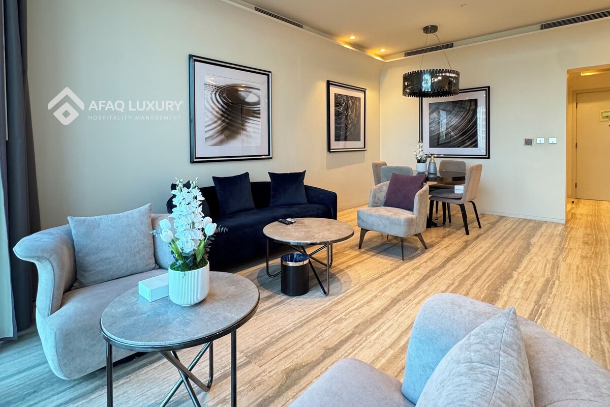 A modern hotel lobby with a sofa, armchairs, a coffee table, and artwork on the walls.
