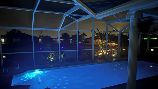 Una piscina con un recinto in vetro, vista sul cielo notturno e sullo skyline in lontananza.