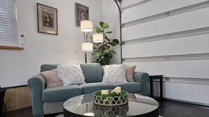 Un soggiorno con un divano verde, un tavolino da caffè nero e una pianta in vaso.