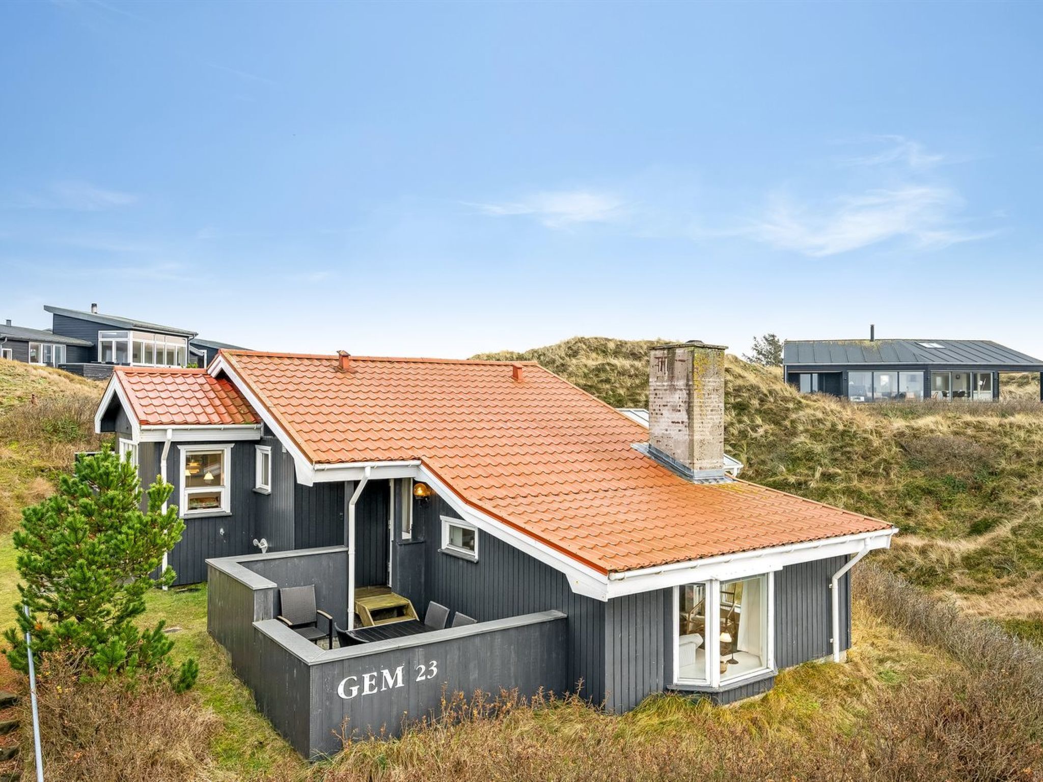 A modern house with a sloped roof, a chimney, and a nameplate reading "GEM 23".