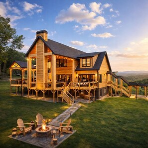 Une grande maison en bois dotée de plusieurs terrasses et d’un espace aménagé avec un foyer.