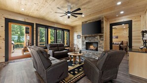 A spacious living room with a fireplace, wooden ceiling, and large windows. - Large Luxury Cabin Hot Tub, Fireplaces, Game Room, & Views. (Talking Rock)