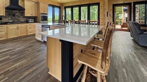 A spacious kitchen with wooden cabinets, a large island, and a stone fireplace. - Large Luxury Cabin Hot Tub, Fireplaces, Game Room, & Views. (Talking Rock)