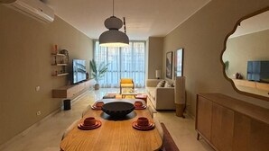 A modern living room with a dining table, sofa, and TV. - Chic 2BR Serviced Apart Pool view Sodic Villette (Cairo Governorate)