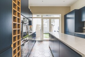 Eine moderne Küche mit Kochinsel, integrierten Regalen und Blick ins Freie.