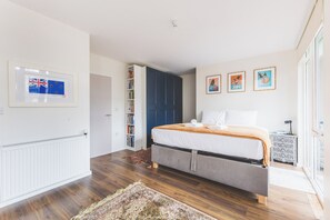 A bedroom with a bed, a wardrobe, a radiator, a bookshelf, and framed artwork on the wall. - Stylish 4BDR Home Near South Acton With Parking (Greater London)