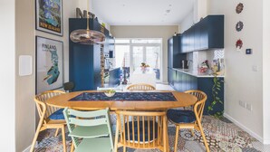 Een moderne keuken met donkere kastjes, een centraal eiland en een eetgedeelte met een houten tafel en stoelen.