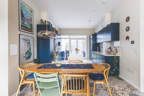 Eine moderne Küche mit dunklen Schränken, einer zentralen Kochinsel und einem Essbereich mit Holztisch und Stühlen.