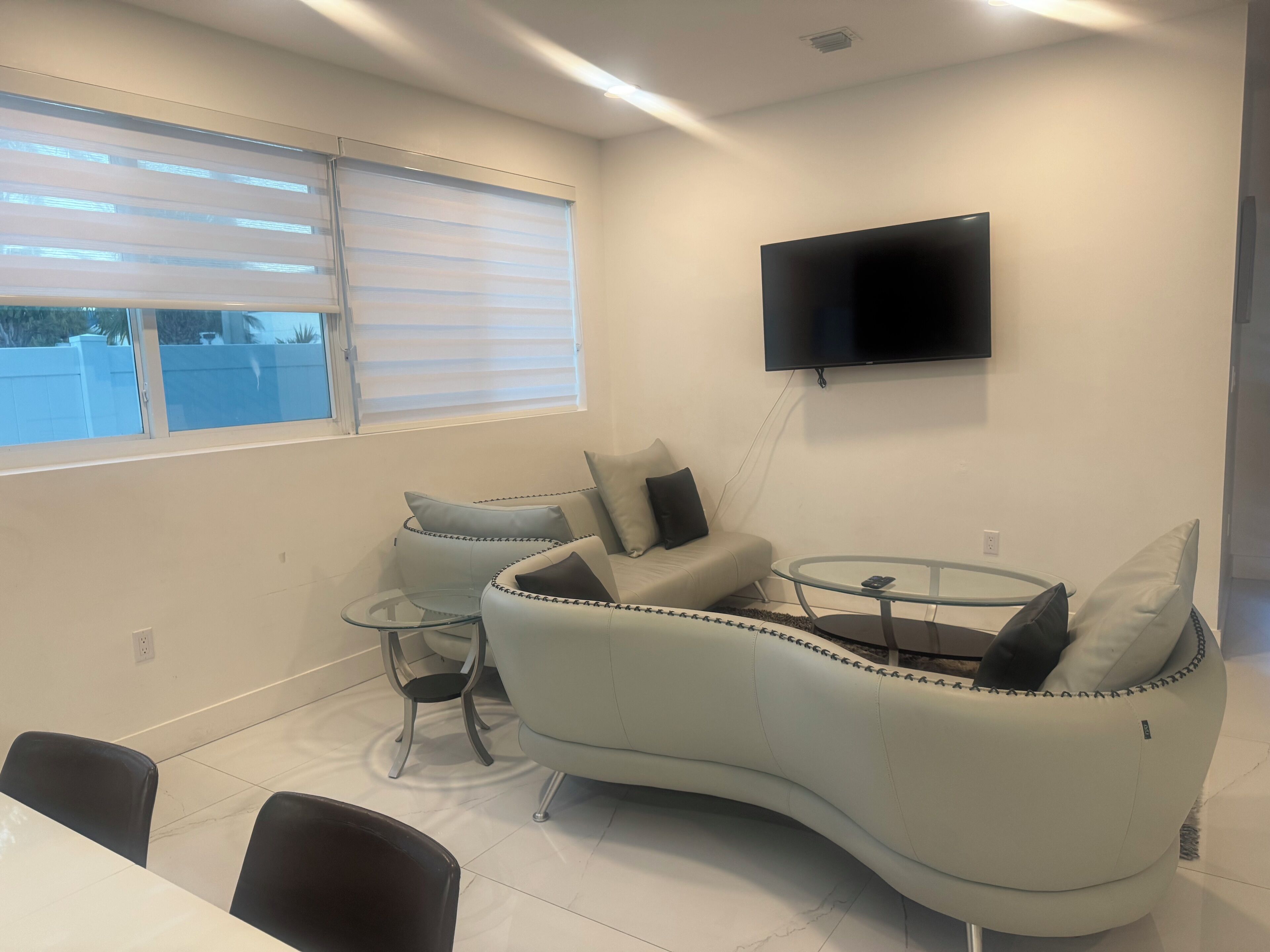 Un salon moderne avec un canapé aux lignes courbes, une table basse en verre et un téléviseur à écran plat fixé au mur.