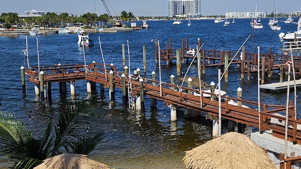 A marina with wooden docks and thatched umbrellas, boats in the background, and a clear view of the water. - 106 Deluxe Studio Suite in waterfront hotel in Singer Island, FL (Riviera Beach)
