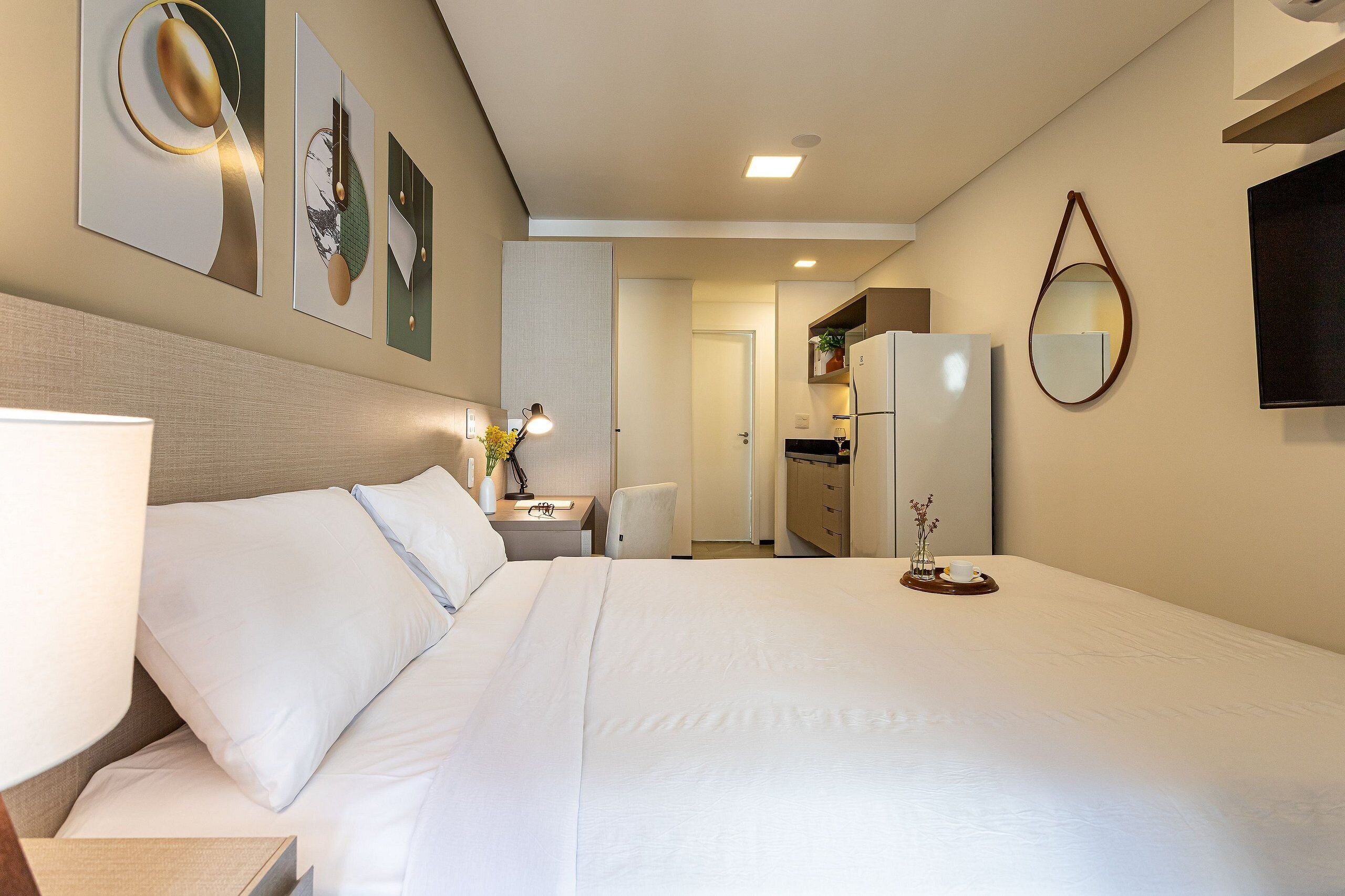 Ein Hotelzimmer mit einem großen Bett, einem Nachttisch mit Lampe, einem Sessel, einem kleinen Tisch mit Vase und einem Spiegel an der Wand.