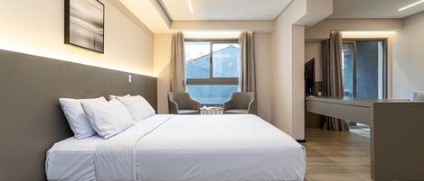 A modern hotel room with a large bed, a desk, and a view of the city.