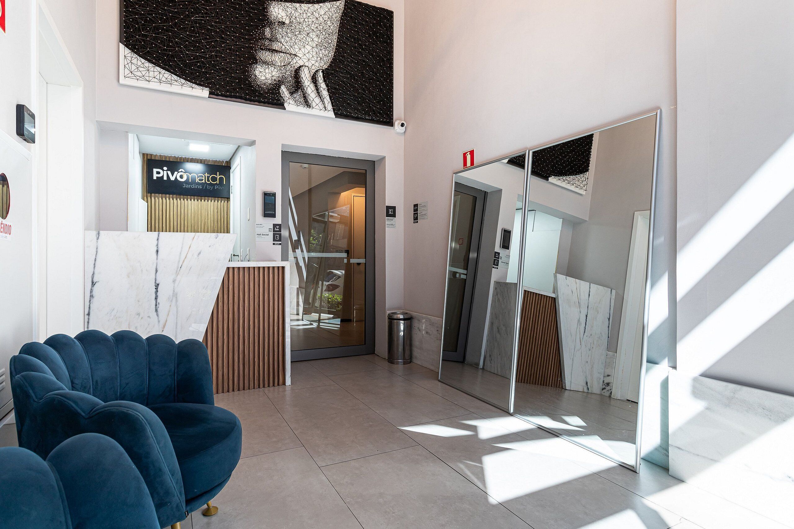 A reception area with a marble counter, a blue chair, and a large mirror.