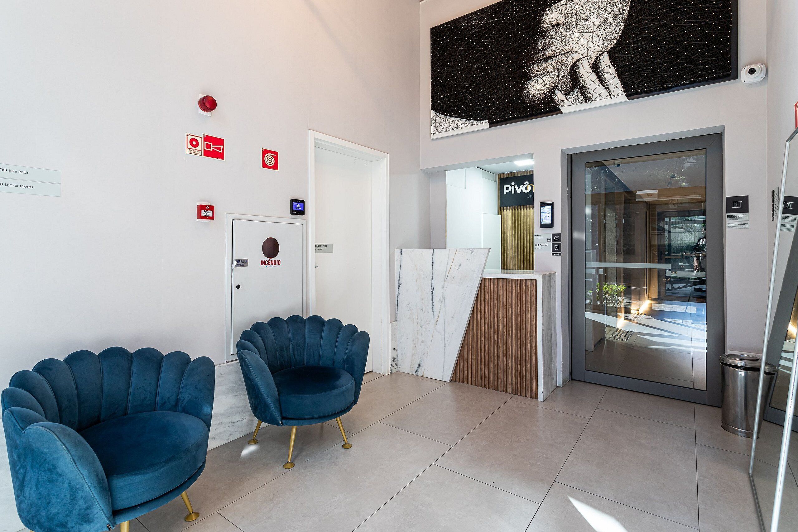 A reception area with a marble reception desk, a digital screen, and a door leading to a room.