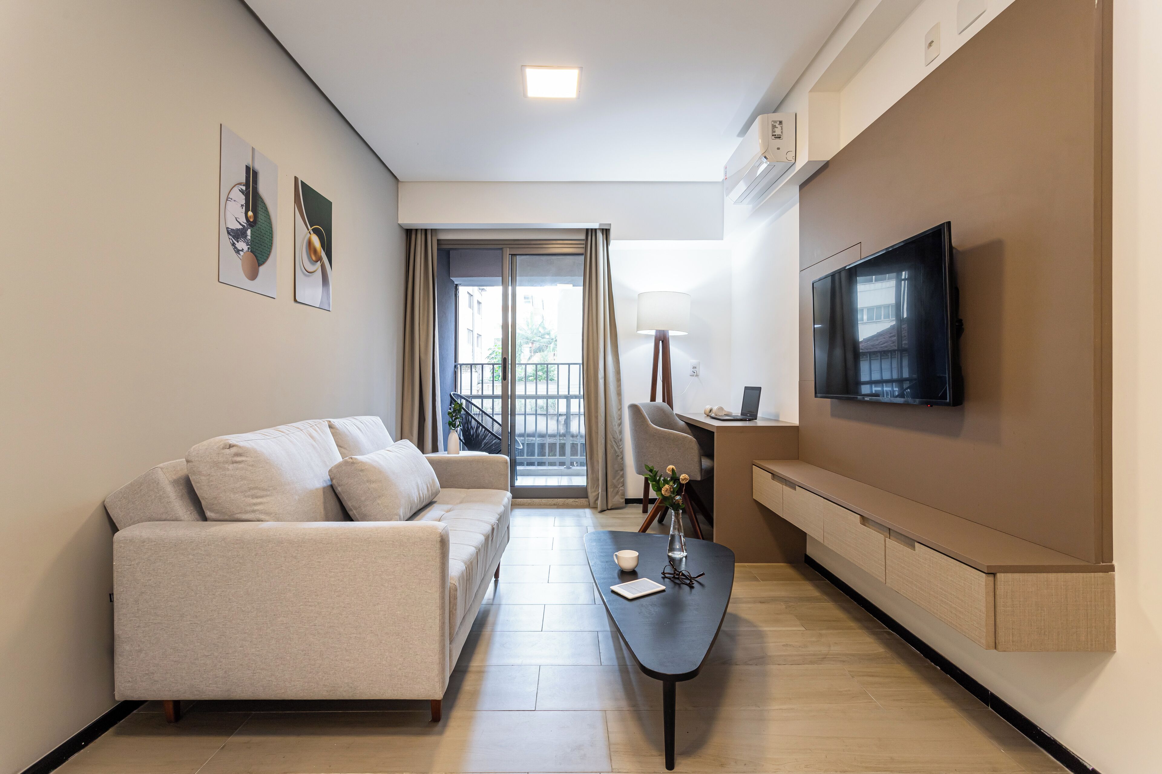 Un salon moderne comprenant un canapé, une table basse, un téléviseur et un espace bureau.