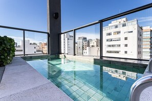 A rooftop pool with a city view, clear sky, and modern buildings. - Pivô Jardins by Viva - Apartamentos Novos e Modernos (São Paulo)