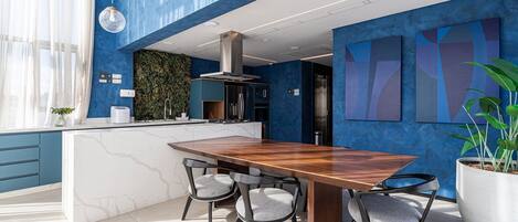 Una cocina moderna con una isla de mármol, dos sillas y una gran mesa de comedor.