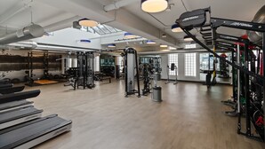 Un gimnasio con equipo de ejercicio, cintas de correr y jaulas para pesas.