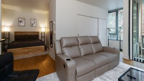 Una sala moderna con un sofá, una cama y una mesa de centro de vidrio.