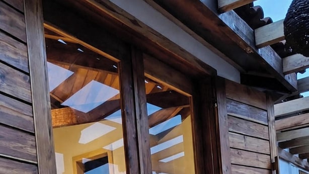 A wooden exterior with large glass doors leading to an interior space.
