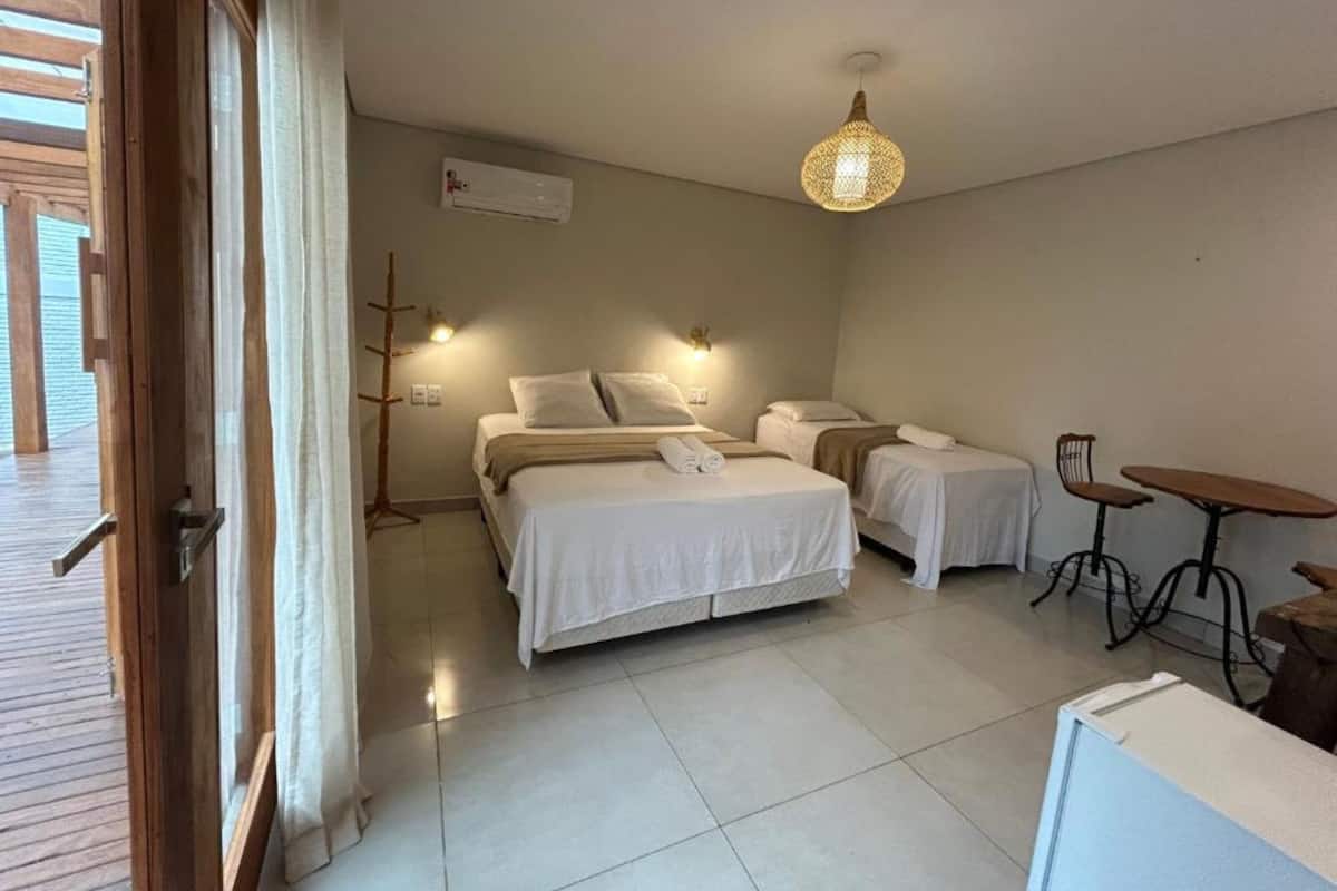 Habitación de hotel con dos camas, una mesita, una silla y una lámpara en el techo.