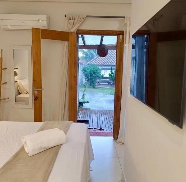 A bedroom with a bed, a wooden door, a window, and a view of a courtyard.