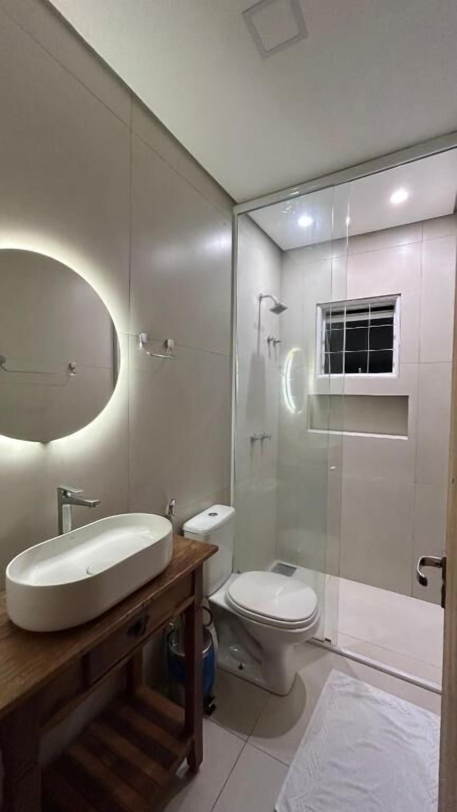 A modern bathroom with a large oval sink, a toilet, and a glass-enclosed shower.