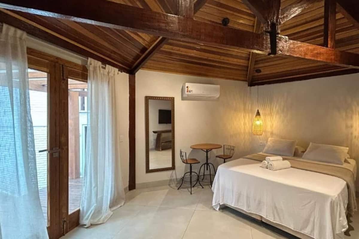 Un dormitorio con cama, mesitas de noche, un espejo y una lámpara colgante.