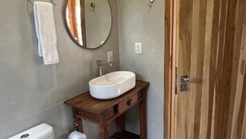 A bathroom with a toilet, sink, wooden vanity, and a wooden door.