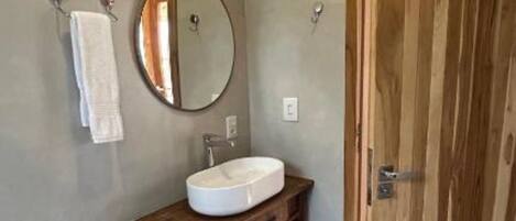 Un baño con inodoro, lavamanos, tocador de madera y puerta de madera.