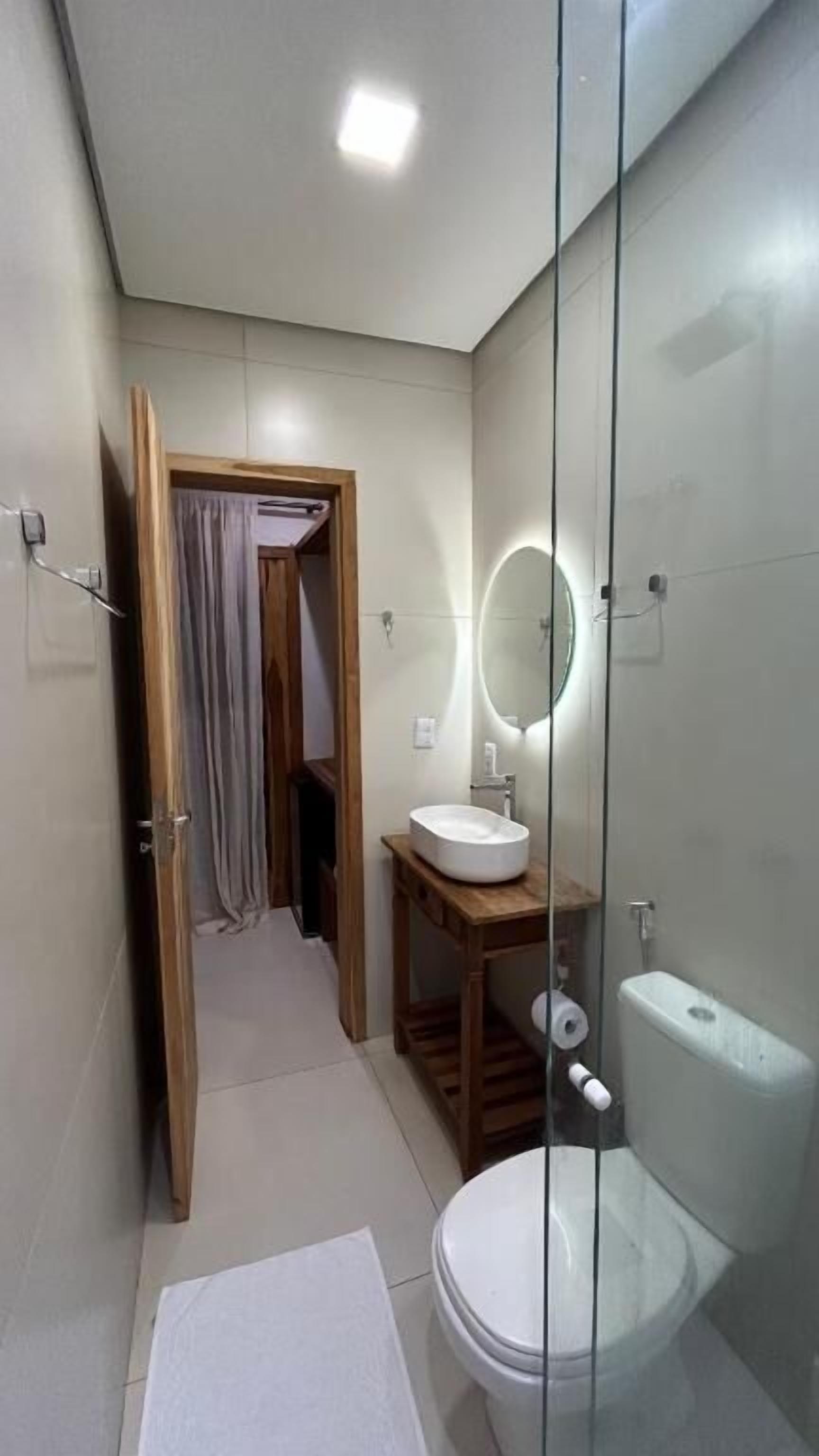 Un baño moderno con cabina de ducha de vidrio, tocador de madera y un inodoro blanco.