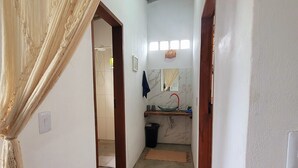 A hallway leading to a bathroom with a shower, a sink, and a mirror. - New house in the heart of the Cerrado biome, easy access and 5 minutes from several waterfalls. (Alto Paraíso de Goiás)
