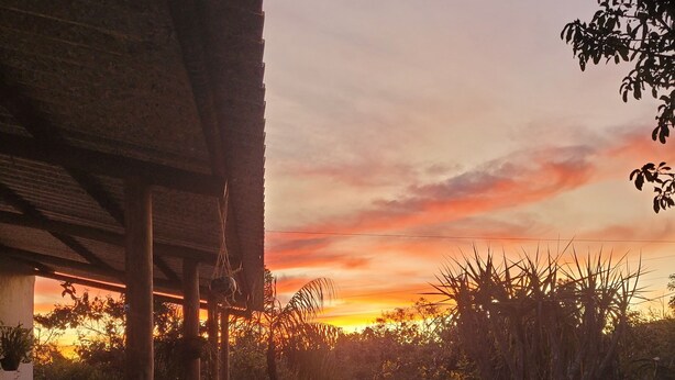 A covered outdoor dining area with a view of the sunset. - New house in the heart of the Cerrado biome, easy access and 5 minutes from several waterfalls. (Alto Paraíso de Goiás)
