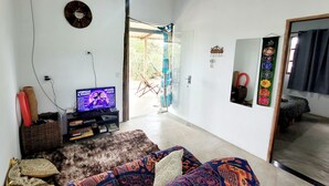 A living room with a television, a sofa, a wicker basket, and a mirror. - New house in the heart of the Cerrado biome, easy access and 5 minutes from several waterfalls. (Alto Paraíso de Goiás)