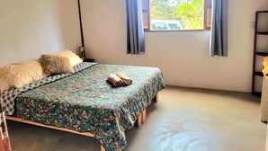 A bedroom with a bed, a window with curtains, and a wooden floor. - New house in the heart of the Cerrado biome, easy access and 5 minutes from several waterfalls. (Alto Paraíso de Goiás)