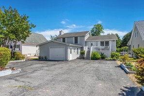 A residential driveway leading to a house with a garage, a covered porch, and a well-maintained lawn. - Waterfront Getaway with Boat Slip (Ocean Pines)