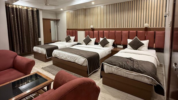 Une chambre d’hôtel moderne équipée de deux lits, d’un canapé, d’une table basse et d’un ventilateur de plafond.
