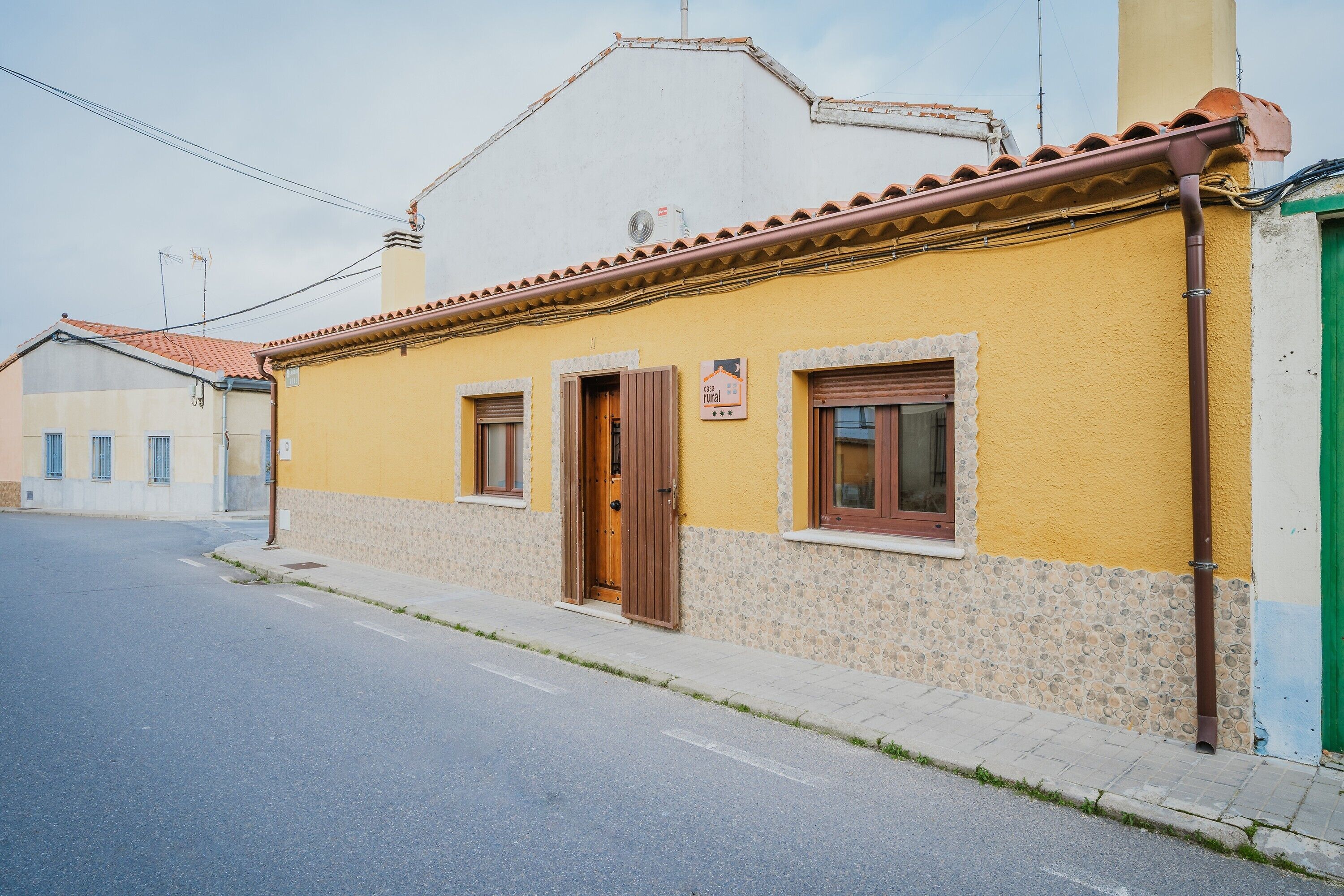 A yellow building with a tiled roof, a wooden door, and a small window.