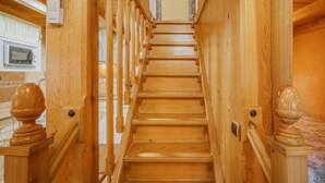 A wooden staircase with a handrail, a wall-mounted intercom, and a microwave visible on the left.