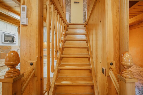 A wooden staircase with a handrail, a wall-mounted intercom, and a microwave visible on the left.
