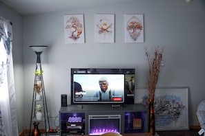 A living room with a flat-screen TV, a tall floor lamp, and three framed artworks on the wall. - Family & Work-Friendly, Backyard & Garage, Near Sanford & West Acres, Breakfast (Fargo)