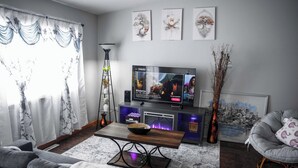 Ein Wohnzimmer mit Flachbildfernseher, einer Couch, einem Couchtisch und einem Sessel.
