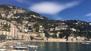 A coastal town with a marina filled with boats, a beach, and buildings on a hillside. - Apartment Ange Gardien, swimming pool, panoramic sea view in Villefranche sur Mer (Villefranche-sur-Mer)