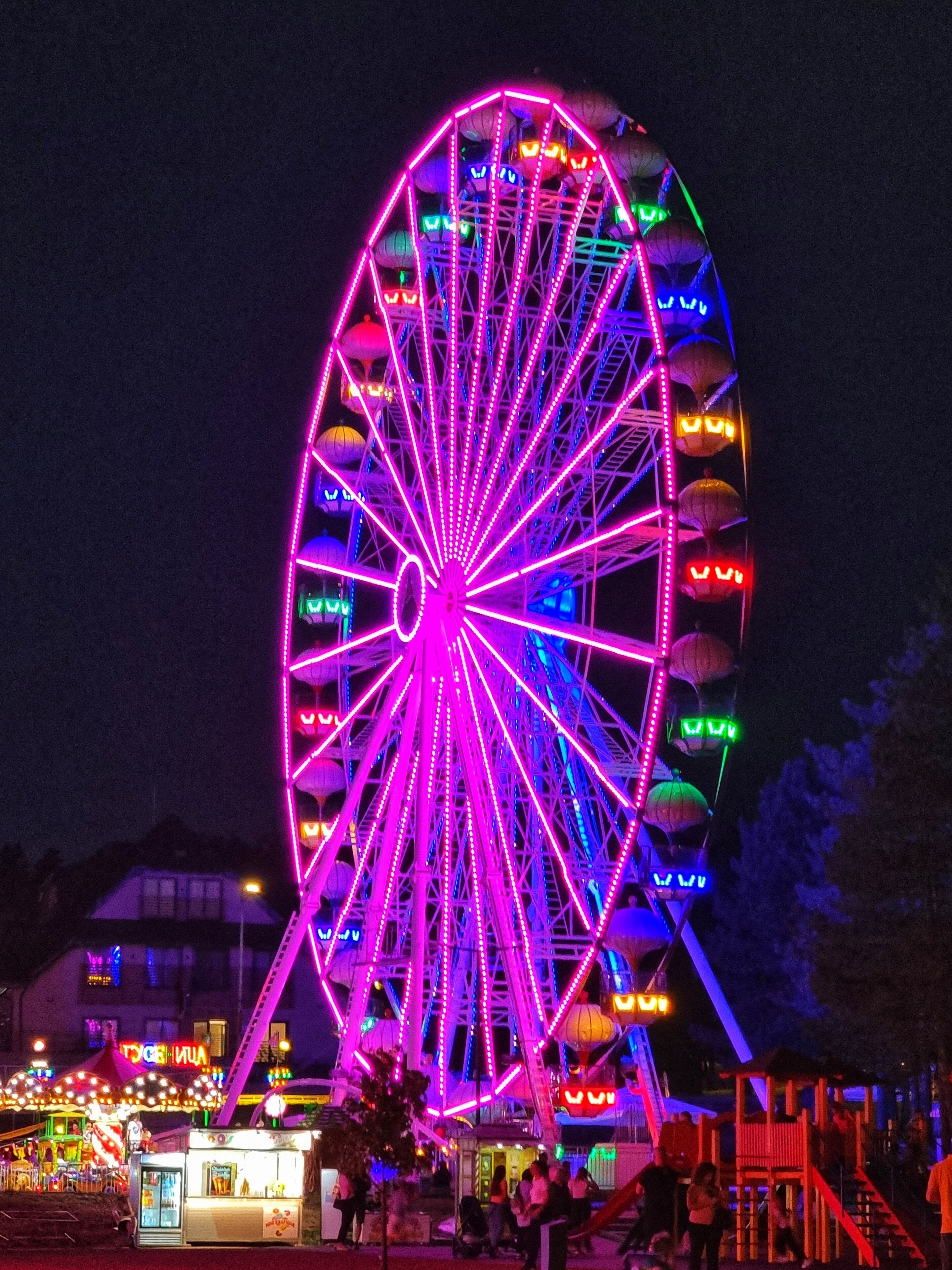Ein großes Riesenrad mit bunten Lichtern bei Nacht.