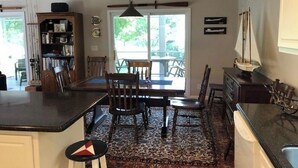 Cozinha com área de jantar, estante de livros e decoração náutica.